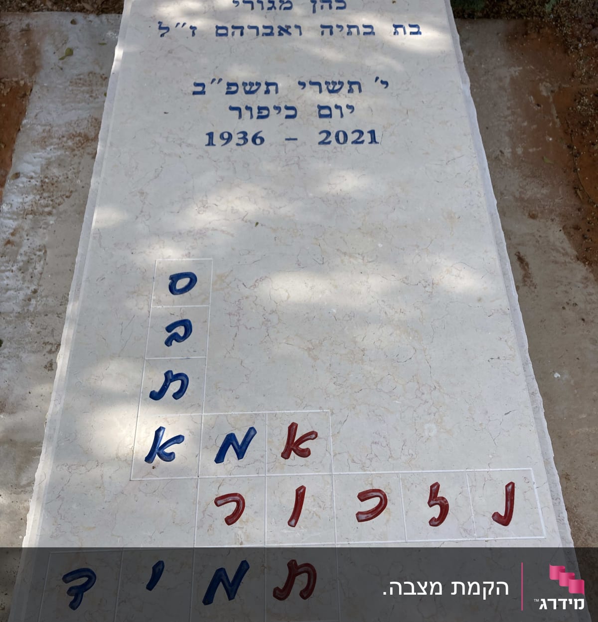 מצבה עם כיתוב בעברית ותשבץ אותיות צבעוני